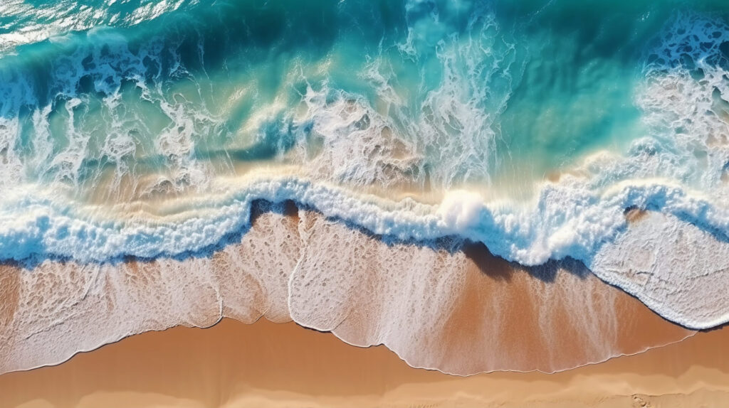 Luftaufnahme einer unberührten Küste mit türkisblauem Wasser, das sanft an einen goldenen Sandstrand rollt.