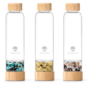 Drei Glasflaschen mit Bambusdeckeln und separaten Kammern, gefüllt mit verschiedenen Edelsteinmischungen, nebeneinander aufgereiht.