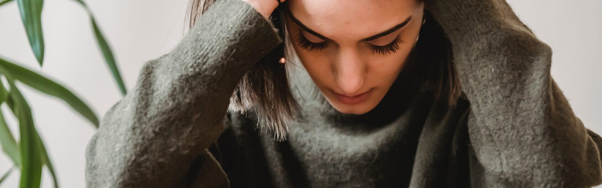 Frau mit Händen am gesenktem Kopf.