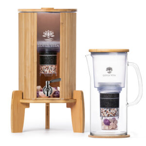Ein Stand-Wasserfilter aus Bambus neben einer gläsernen Wasserkaraffe mit Filter, beide von Lotus Vita.