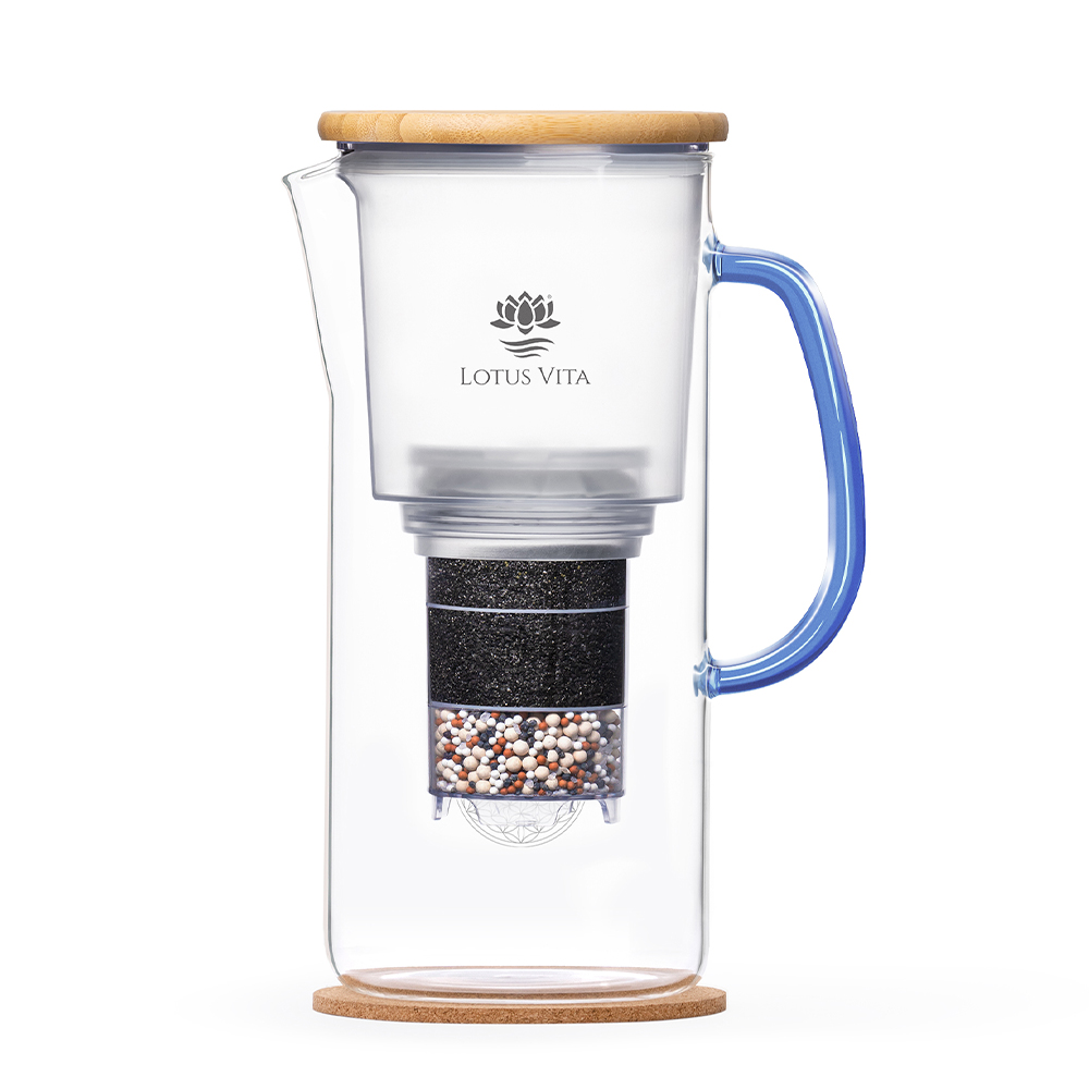 Ein Glas-Wasserfilterkrug mit blauem Henkel und Holzdeckel steht auf einem Korkuntersetzer und zeigt die Filterkartusche im Inneren.